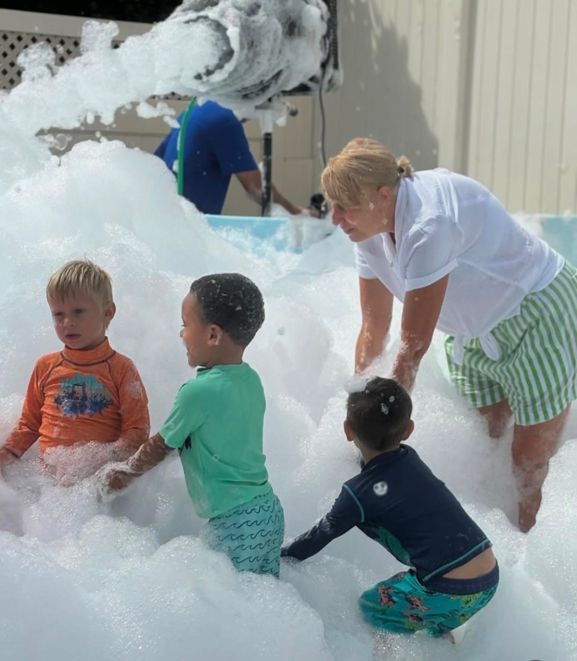 Young children and an adult enjoying a backyard foam party